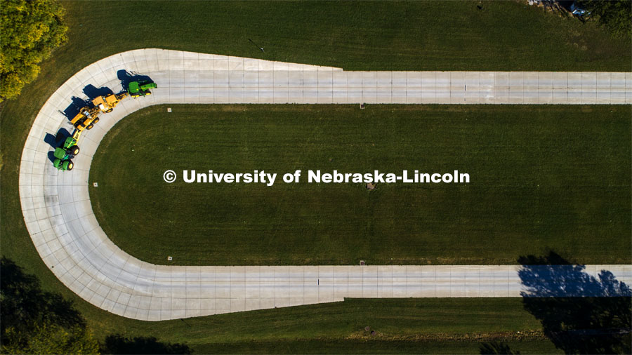 A tractor pulls the test car (yellow) and an additional tractor for weight as it rounds the test track on east campus. The University of Nebraska Tractor Test Laboratory (NTTL) is the officially designated tractor testing station for the United States. It has operated for more than 100 years. East Campus. September 28, 2020. Photo by Craig Chandler / University Communication.