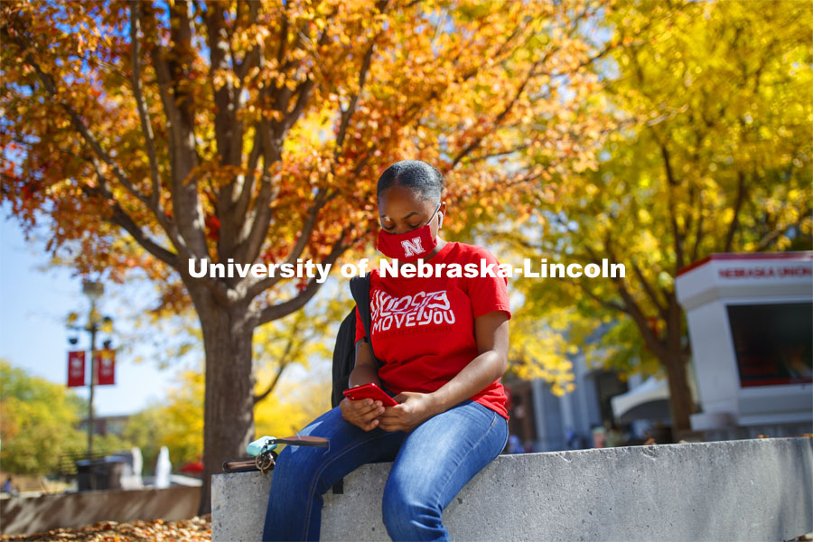 Brianna Rosalez, a freshman from Kansas City, enjoys the sunshine as she checks her phone during the noon hour outside the Nebraska Union. City Campus. October 7, 2020. Photo by Craig Chandler / University Communication.