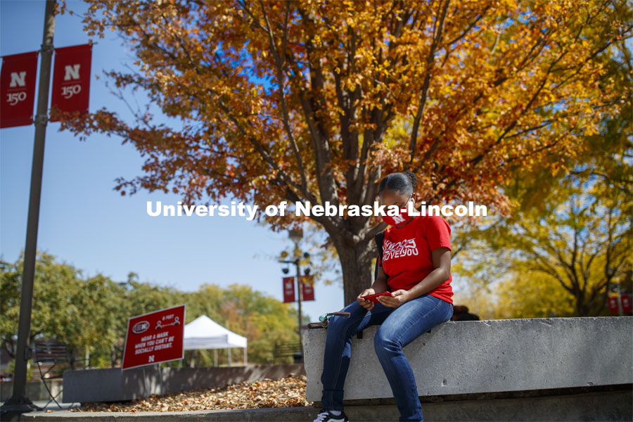 Brianna Rosalez, a freshman from Kansas City, enjoys the sunshine as she checks her phone during the noon hour outside the Nebraska Union. City Campus. October 7, 2020. Photo by Craig Chandler / University Communication.