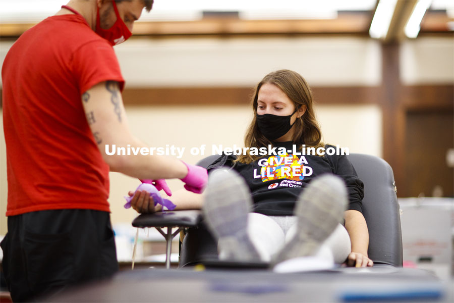 Kacey Heidbrink, a junior from Beatrice, watches as Brandon Thelen preps her arm to donate. Students donate in the Homecoming Blood Drive in the Nebraska Union ballroom on city campus. October 27, 2020. Photo by Craig Chandler / University Communication.