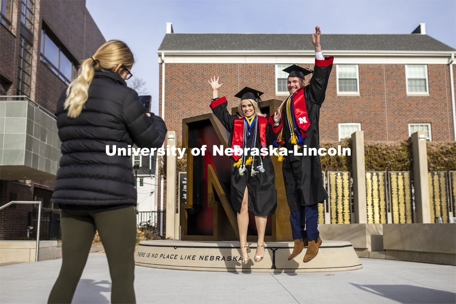 Paige Heitkamp, a senior in Criminal Justice from Sioux Falls, SD, and Tucker Thompson, a senior in secondary education from Highland Park, Illinois, jump for joy as they are photographed by Jessica Kistaitis in front of The Value of N sculpture at the alumni center. December 8, 2020. Photo by Craig Chandler / University Communication.
