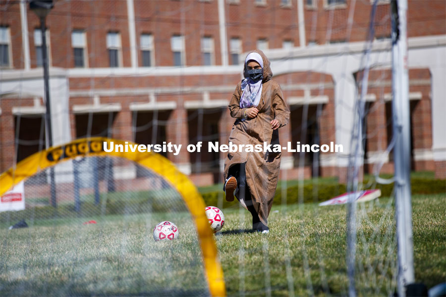 One young woman kicks a soccer ball outside the Nebraska Union. Students have fun at the Spring Breakout, a midday festival with free games, music, and prizes. 300 free t-shirts for participants. March 29, 2021. Photo by Craig Chandler / University Communication.