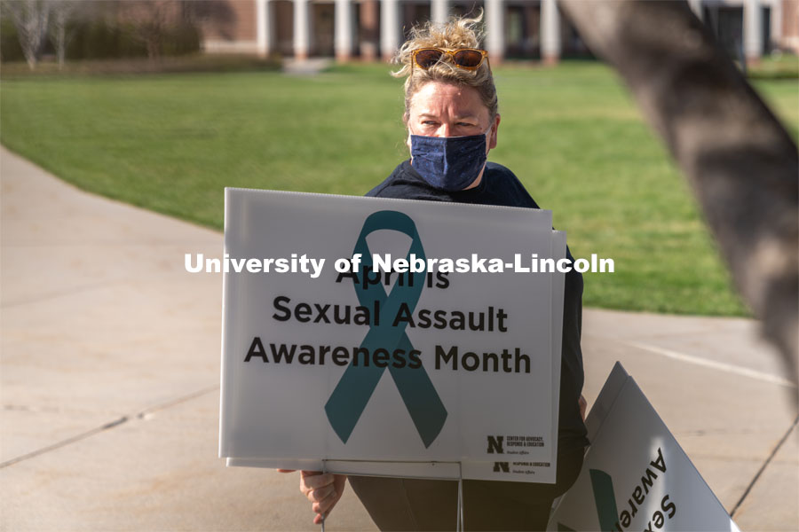 CARE Advocate Melissa Wilkerson organizes signs before placing them at the Nebraska Union Greenspace. Flags and signs are placed in the Nebraska Union Greenspace to promote Sexual Assault Awareness Month. April 4, 2021. Photo by Jordan Opp for University Communication.