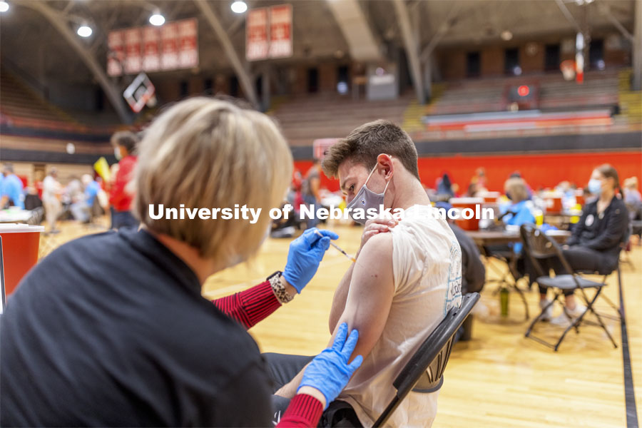 Sam Raabe receives his first dose of vaccine during a COVID-19 vaccination clinic April 20 at the Coliseum. Vaccine clinic in the Coliseum with a free food and goodies tent outside. April 20, 2021. Photo by Craig Chandler / University Communication.