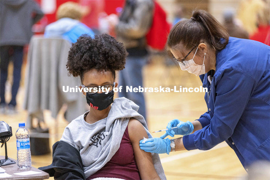 Meklit Aga receives her first dose of vaccine during a COVID-19 vaccination clinic April 20 at the Coliseum. Vaccine clinic in the Coliseum with a free food and goodies tent outside. April 20, 2021. Photo by Craig Chandler / University Communication.