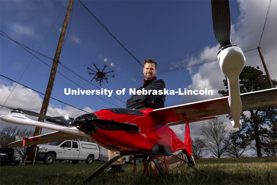 Justin Bradley, Assistant Professor in Computer Science and Engineering, is a NSF CAREER award winner. He is shown with a Savant fixed wing VTOL as a quadcopter hovers overhead. April 21, 2021. Photo by Craig Chandler / University Communication.