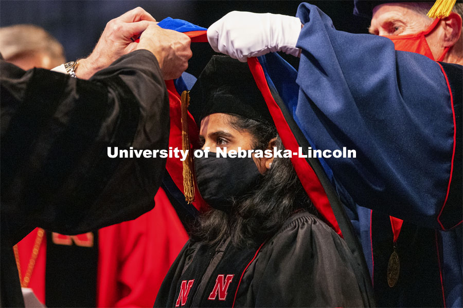 Manny Saluja is hooded by Professor Scott Sattler and Tim Carr, Associate Vice Chancellor and Dean for Graduate Studies. Graduate Commencement at Pinnacle Bank Arena. May 7, 2021. Photo by Craig Chandler / University Communication.