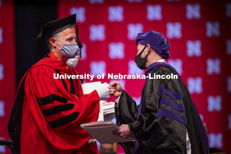 Adam Podraza receives a fist bump from Dean Richard Moberly after receiving his hood. College of Law Graduation at Pinnacle Bank Arena. May 7, 2021. Photo by Craig Chandler / University Communication.