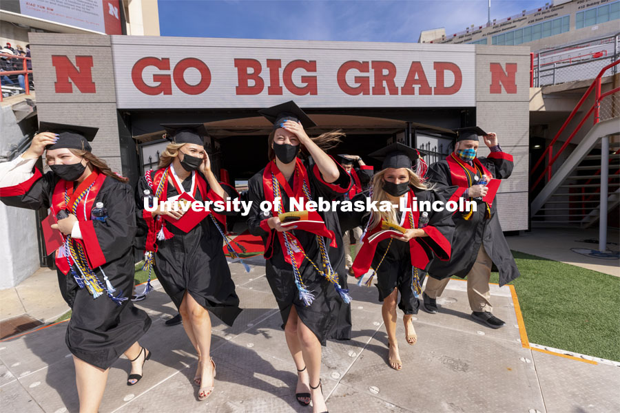 Graduates walk onto the field as they hang on to their mortar board and stoles in the brisk wind. UNL Commencement in Memorial Stadium. May 8, 2021. Photo by Craig Chandler / University Communication.