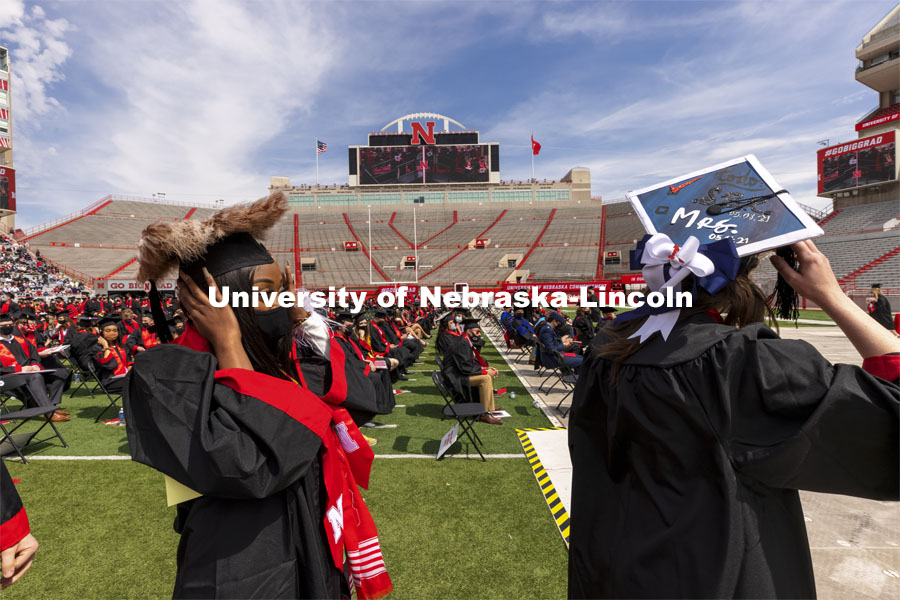 Aubryanna Cooper-Wilborn and Robin Coleman hang on to their mortar boards as they proceed to receive their College of Business diplomas. UNL Commencement in Memorial Stadium. May 8, 2021. Photo by Craig Chandler / University Communication.