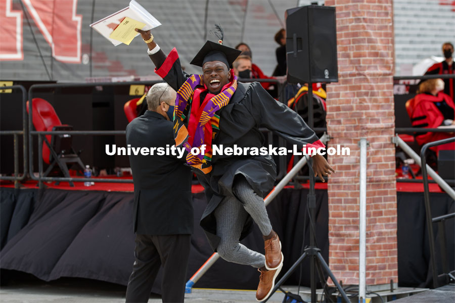 DeShawn McGary lets his graduation joy show as he walks off the ramp. McGary, who received a CoB degree, had removed his mask for his grad photo and leaped before putting it back on. UNL Commencement in Memorial Stadium.  May 8, 2021. Photo by Craig Chandler / University Communication.  