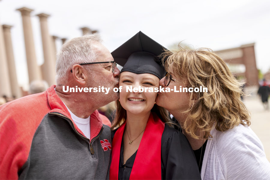 Mike and Judy Hartong kiss their daughter, Samantha, while taking photos with family and friends after the ceremony. UNL Commencement in Memorial Stadium. May 8, 2021. Photo by Craig Chandler / University Communication.