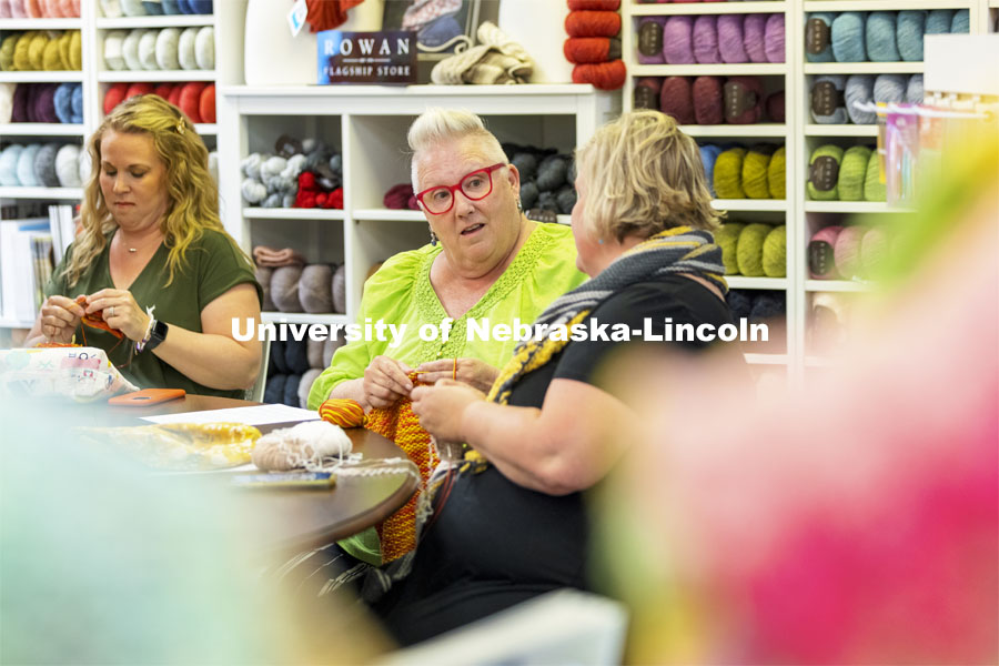 Rene Botts, center, talks with Stacy Stupka as Maggie Rawlings knits in the background. The three were part of a group knitting at Knit-Paper-Scissors in south Lincoln. Nebraska marketing professor Andre F. Maciel was intrigued when he chanced upon a knitters’ group in Tucson, Arizona, in 2011, during his doctoral program. He found knitting’s resurgence reflects women’s desire to confront inequality. June 9, 2021. Photo by Craig Chandler / University Communication.