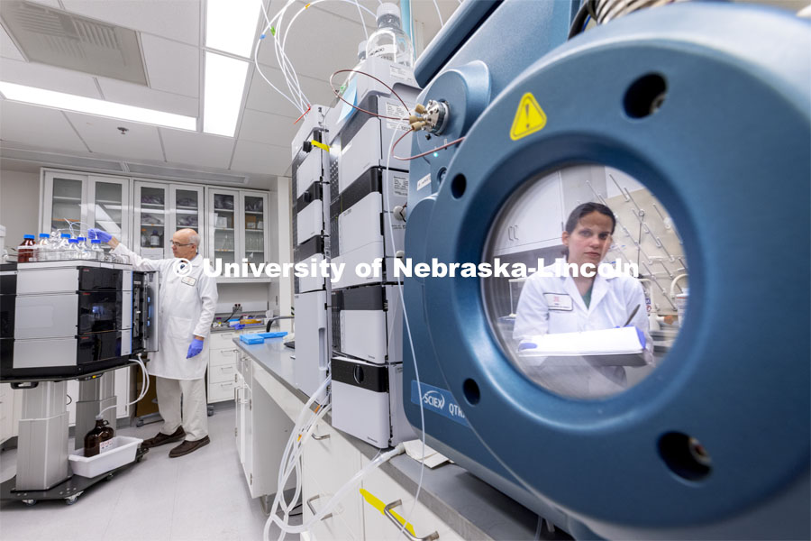 Lab Manager Anne Fischer is reflected in a port of a spectrometer as Mike Naldrett works in the background in the Proteomics and Metabolomics lab in Beadle Hall. Nebraska Center for Biotechnology. June 25, 2021. Photo by Craig Chandler / University Communication.