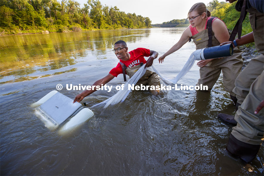 McNair scholar Seth Caines, summer research scholar Moriah Brown from Howard University and Meredith Sutton, graduate student in environmental engineering, use a floating sieve to sample water in the Elkhorn River. They are working with Professor Shannon Bartlet-Hunt researching textiles as a source of microplastic fibers to Nebraska streams. July 2, 2021. Photo by Craig Chandler / University Communication.