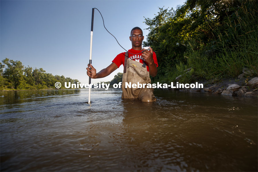 McNair scholar Seth Caines, summer research scholar uses a flowmeter to sample the speed of the Elkhorn River. He is working with Professor Shannon Bartlet-Hunt researching textiles as a source of microplastic fibers to Nebraska streams. July 2, 2021. Photo by Craig Chandler / University Communication.