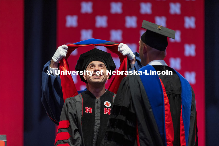 Ali Jamal Mazaltarim watches his doctoral hood being placed over his head. Summer Graduate Commencement at Pinnacle Bank Arena. August 13, 2021. Photo by Craig Chandler / University Communication.