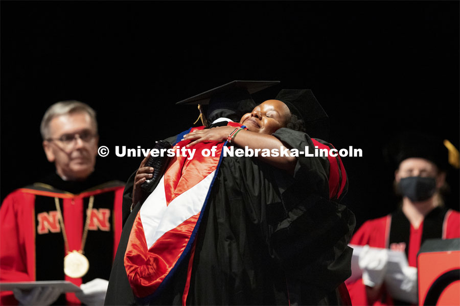 2020 graduate Abeygael Wachira hugs Professor Michael School after she returned to campus to receive her doctoral hood. Summer Graduate Commencement at Pinnacle Bank Arena. August 13, 2021. Photo by Craig Chandler / University Communication.