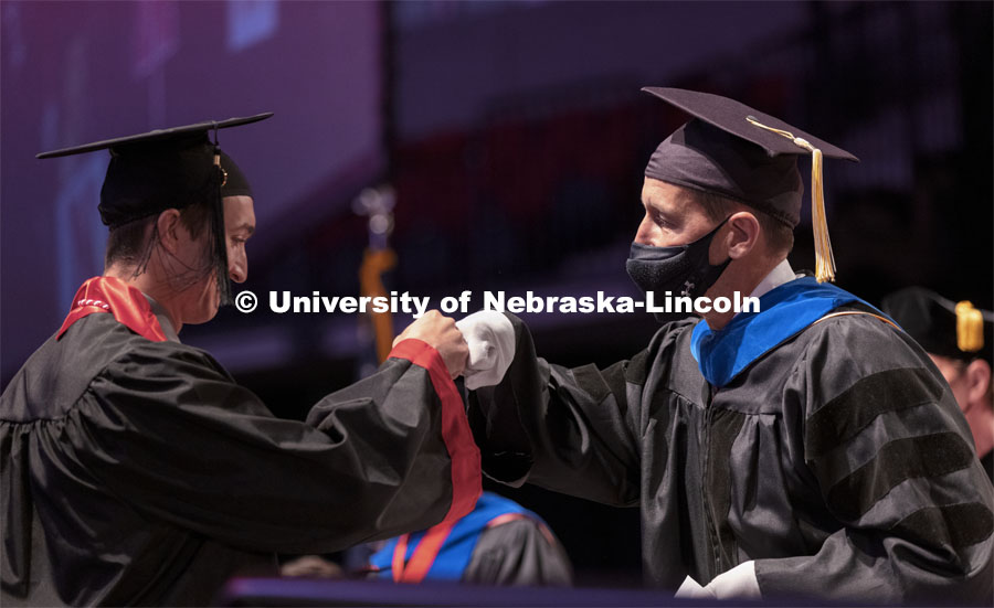 Daniel Linzell, associate dean for graduate and international programs in the College of Engineering and Leslie D. Martin Professor of Civil and Environmental Engineering, fist bumps an engineering graduate as he hands out diplomas. Undergraduate Commencement at Pinnacle Bank Arena. August 14, 2021. Photo by Craig Chandler / University Communication.