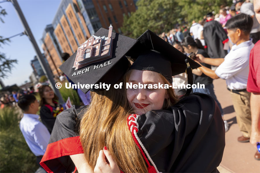 One last hug for 2020 architecture graduates Leia Farrens and Margaret Gies. Gies decorated her mortar board with a rendering of Architecture Hall. Undergraduate Commencement at Pinnacle Bank Arena. August 14, 2021. Photo by Craig Chandler / University Communication.
