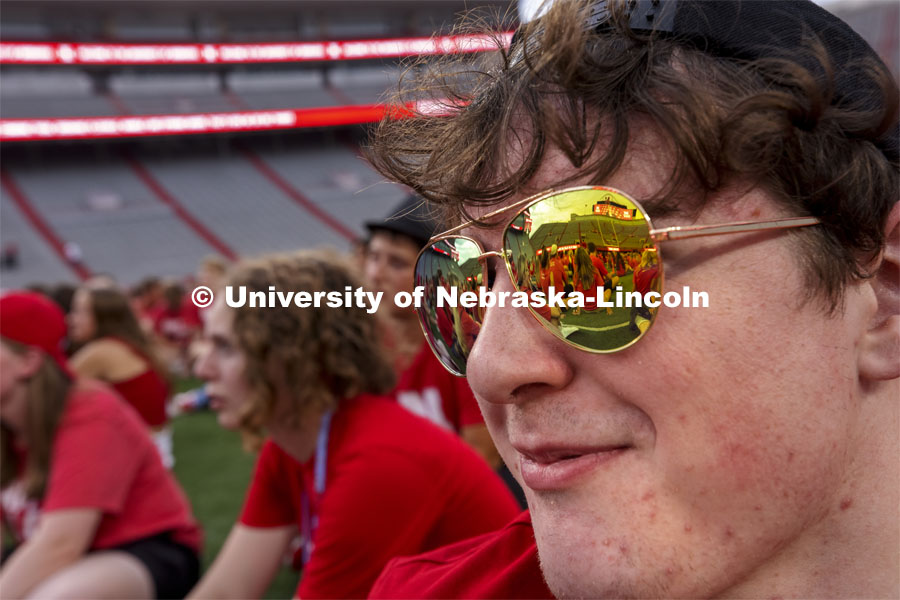 Grady Wright, a first-year student from Minden, NE, listens as ASUN President Batool Ibrahim on the video board is reflected in his sunglasses. Tunnel Walk for freshman (class of 2025) and incoming new students. First year students tunnel walk. August 20, 2021. Photo by Craig Chandler/ University Communication.