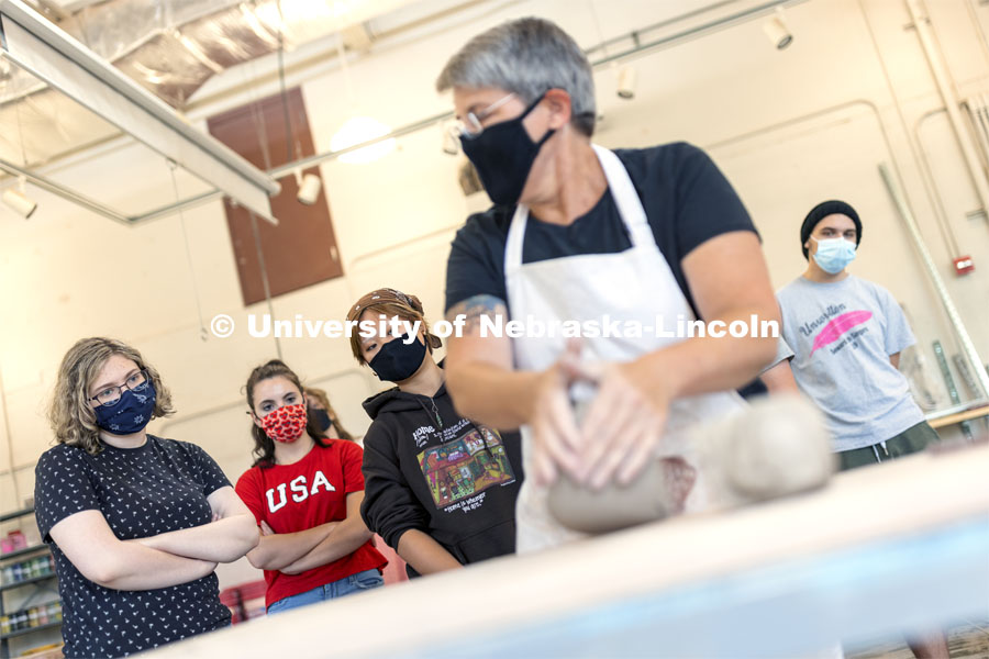 Students watch over the shoulder of Margaret Bohls, associate professor of art, so they can learn correct hand placement to wedge a lump of clay in the beginning wheel class. First day of classes for fall semester. August 23, 2021. Photo by Craig Chandler / University Communication.