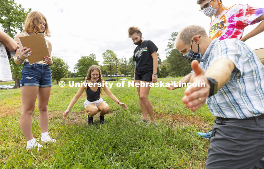 Emily Nelson, a sophomore from Papillion, describes a bed of dandelions to Joe Dauer, associate professor in the School of Natural Resources, as his class describes populations of plants outside Hardin Hall. First day of classes for fall semester. August 23, 2021. Photo by Craig Chandler / University Communication.
