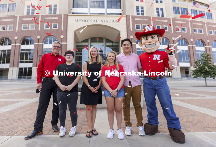 Chancellor Ronnie Green and Herbie stand outside Memorial Stadium on either side of the Voluntary COVID-19 Vaccine Registry grand prize winners (from left) Alex Chytil, Jenna Huttenmaier, Sidney Vincent and Dan Nguyen. Not pictured are Griselda Aragon and Samuel Flint. Vaccine winners. August 23, 2021. Photo by Craig Chandler / University Communication.