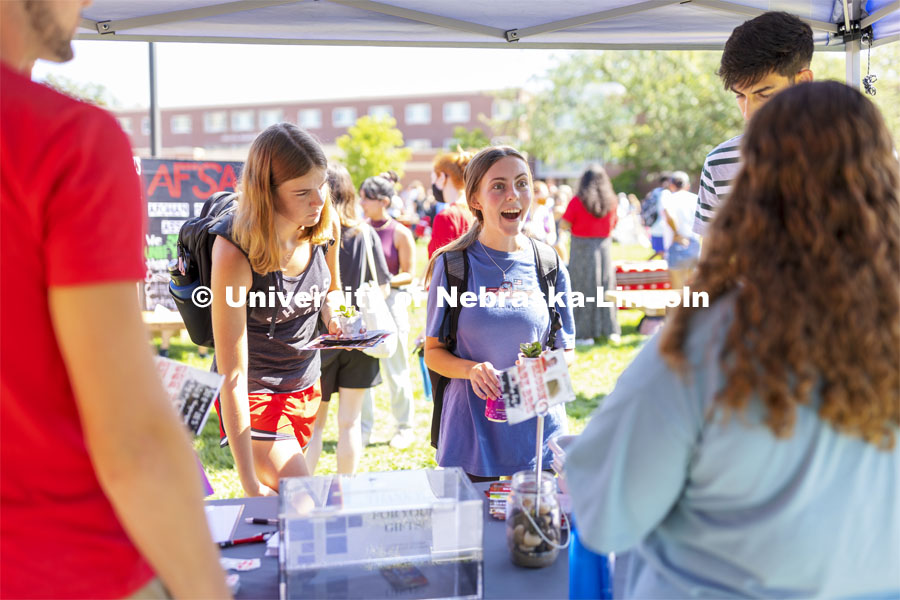 Morgan Tracy, a freshman from St. Louis, reacts as she finds out the person from Lutheran Student Center is also from St. Louis. Tracy and Baylee Carter, a freshman from ?Wichita, Kan., were collecting small plants for their rooms at the booth. Club Fair at City Campus. More than 130 recognized student organizations (RSOs) to join for social, professional and leadership interests. RSO members and officers will be on hand to provide details about their organization and answer questions from prospective new members. August 25, 2021. Photo by Craig Chandler / University Communication