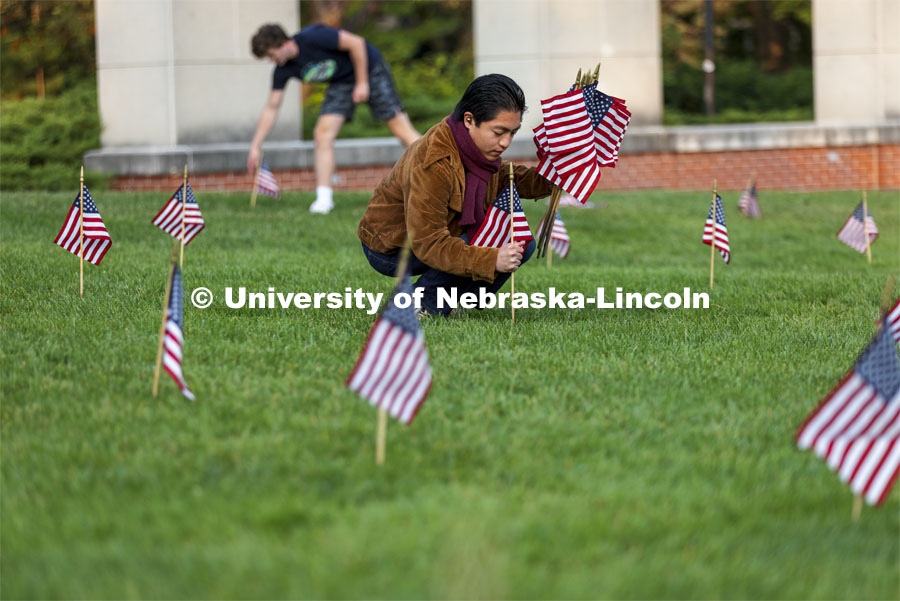 Jerry Saguin, a freshman from San Diego, helps set out flags in the green space north of the Nebraska Union to commemorate 9/11. 9/11 memorials. September 9, 2021. Photo by Craig Chandler / University Communication.