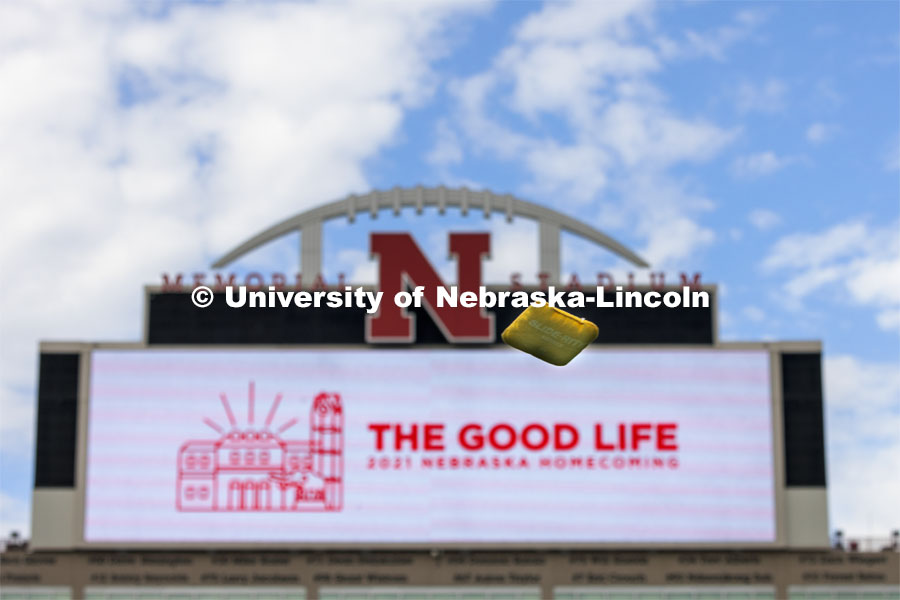 A bag sails through the air against the backdrop of the Memorial Stadium video screen. Homecoming Cornhole Tournament. Teams of two square off against each other in the classic lawn game of cornhole in Memorial Stadium. September 29, 2021. Photo by Craig Chandler / University Communication.