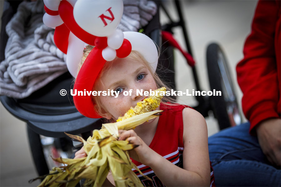 Kennedy Bertsch, 4, of Malcomb, works on an ear of corn while waiting for the parade to begin. Homecoming Parade and Cornstalk Festival. October 1, 2021. Photo by Craig Chandler / University Communication.