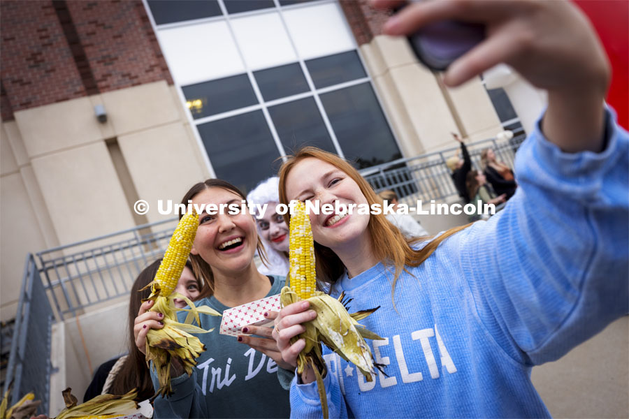 Emma Storms and Erin Stanley pose for a selfie with their Cornstalk Festival roasted corn as Jester competitor Claire Wackel photobombs the shoot. Homecoming Parade and Cornstalk Festival. October 1, 2021. Photo by Craig Chandler / University Communication.