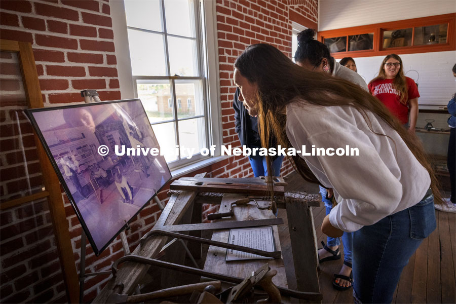 Jean Parker-Morris looks over a photo of students working in the carpentry shop. Her great grandfather was sent to the school and learned carpentry. Students from UNITE tour the Genoa Indian School in Genoa, Nebraska. October 10, 2021. Photo by Craig Chandler / University Communication.