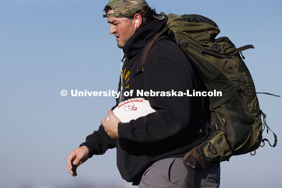 Trevor Stephens, U.S. Marine Corps veteran and a sophomore in secondary education from Council Bluffs, Iowa, walks along Highway 93 westbound from Treynor, Iowa.Stephens carries the game ball, and 20 pounds in his pack, recognizing the 20 veterans that die from suicide each day. Sixth annual The Things They Carry Ruck March, which began at Kinnick Stadium in Iowa City, Iowa, Nov. 17, and finishes at Memorial Stadium on Friday, Nov. 25. The march, which is organized by the University of Nebraska–Lincoln Student Veterans and University of Iowa Veterans Association organizations, is centered on raising awareness of the epidemic of veteran suicide. It also carries the game ball for the Husker-Hawkeye match-up. November 23, 2021. Photo by Craig Chandler / University Communication.