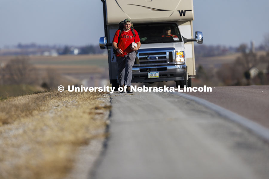 Trevor Stephens, U.S. Marine Corps veteran and a sophomore in secondary education from Council Bluffs, Iowa, walks along Highway 93 westbound from Treynor, Iowa.
Stephens carries the game ball, and 20 pounds in his pack, recognizing the 20 veterans that die from suicide each day. Sixth annual The Things They Carry Ruck March, which began at Kinnick Stadium in Iowa City, Iowa, Nov. 17, and finishes at Memorial Stadium on Friday, Nov. 25. The march, which is organized by the University of Nebraska–Lincoln Student Veterans and University of Iowa Veterans Association organizations, is centered on raising awareness of the epidemic of veteran suicide. It also carries the game ball for the Husker-Hawkeye match-up. November 23, 2021. Photo by Craig Chandler / University Communication.

