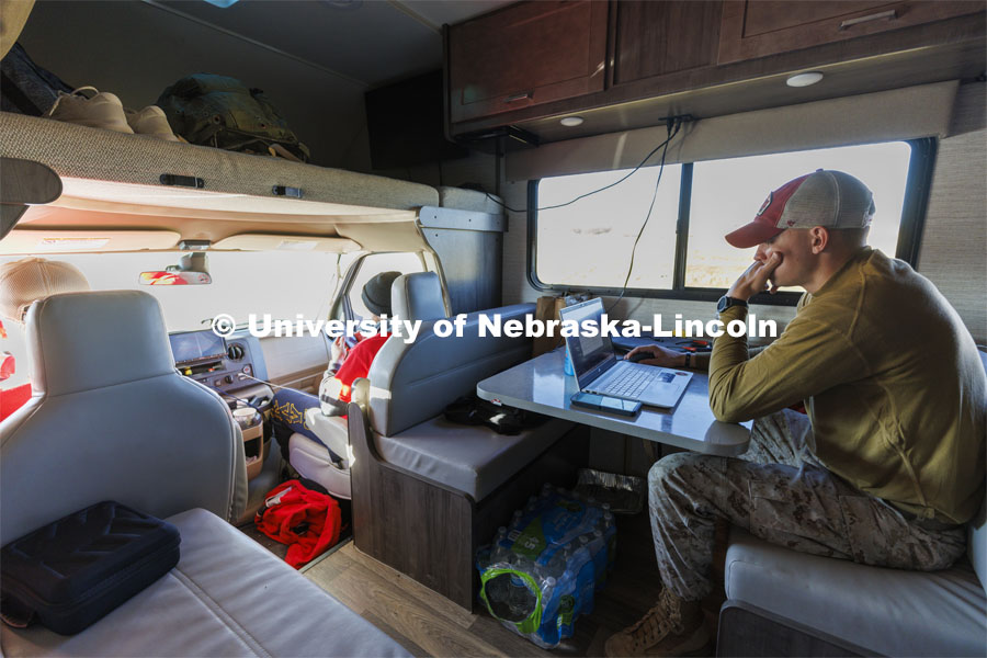 Tyler Kluthe, Marine Corps reservist and a junior construction management major from Lincoln, catches up on homework as he rests in the RV along with Everett Bloom and Dave Rangeloff. The donated RV trails the marcher along the route. Sixth annual The Things They Carry Ruck March, which began at Kinnick Stadium in Iowa City, Iowa, Nov. 17, and finishes at Memorial Stadium on Friday, Nov. 25. The march, which is organized by the University of Nebraska–Lincoln Student Veterans and University of Iowa Veterans Association organizations, is centered on raising awareness of the epidemic of veteran suicide. It also carries the game ball for the Husker-Hawkeye match-up. November 23, 2021. Photo by Craig Chandler / University Communication.