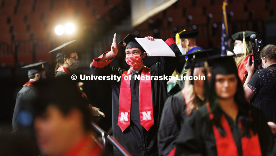 Chase Stubbs gestures to family and friends after receiving his CoJMC diploma. Undergraduate Commencement at Pinnacle Bank Arena. December 18, 2021. Photo by Craig Chandler / University Communication.