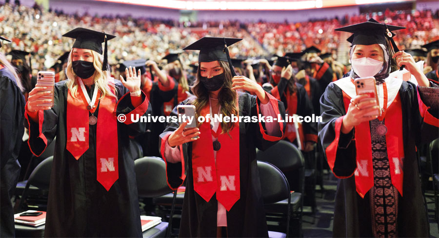 Chancellor scholars Paxton Suzanne Brittingham, Khiana Rose Blizek, and Nur Azhani Nazifa Binti Azhar recorded the moving of their tassels to family and friends. Undergraduate Commencement at Pinnacle Bank Arena. December 18, 2021. Photo by Craig Chandler / University Communication.