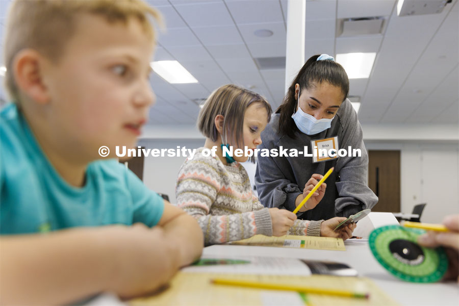 Brisa Rios, a sophomore honors student in psychology and sociology, helps 8-year-old Audrey decode a message using a cipher wheel during a Winter Break 4-H STEM Challenge in Crete, Nebraska. UNL honors students work as winterns for 4-H/Extension winternships and the Galactic Quest activities. January 4, 2022. Photo by Craig Chandler / University Communication.