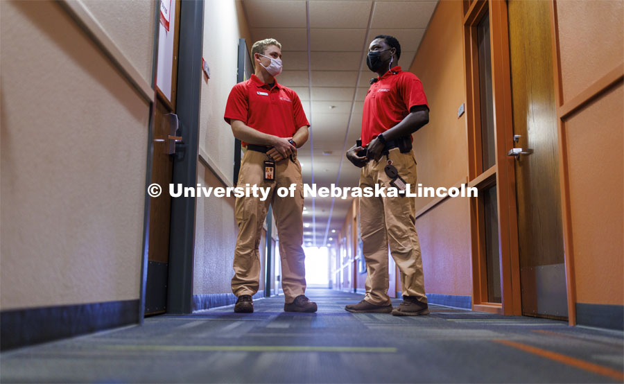 UNLPD Community Service Officers Trevor Caldwell and Komlan Akakpo talk in University Suites hallway. The CSOs are wearing more casual uniforms in 2022. January 7, 2022. Photo by Craig Chandler / University Communication.