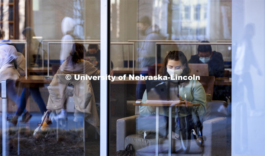 Students walking by are reflected as others study in Love Library. First day of classes for the spring semester. January 18, 2022. Photo by Craig Chandler / University Communication.