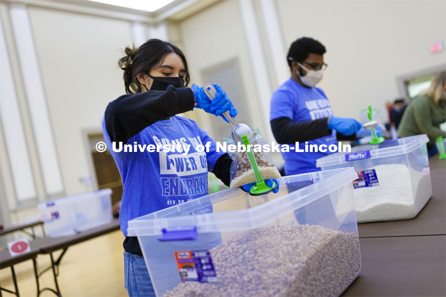 Cynthia Serrano-Ortega adds a scoop of beans to a meal being packed. Volunteers are packing more than 2,000 rice and bean meals that will be distributed to feed the hungry across Nebraska. MLK Volunteers dish up meals for the Food Bank of Lincoln in the Nebraska Union. January 19, 2022. Photo by Craig Chandler / University Communication.