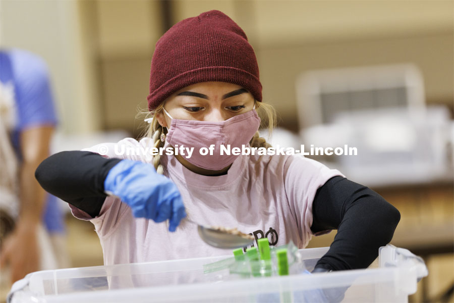 Isela Tercero adds a scoop of beans to a meal being packed in the Nebraska East Union. Nebraska East Union volunteers are packing more than 2,000 rice and bean meals that will be distributed to feed the hungry across Nebraska. The meals are part of the volunteer component of MLK week. January 20, 2022. Photo by Craig Chandler / University Communication.