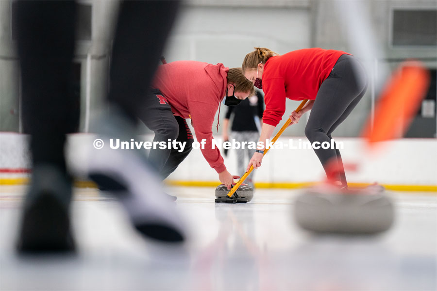 Luke Schroeder (left) Olivia Schuster (right) sweeps during curling practice at the John Breslow Ice Hockey Center. Curling Club. February 1, 2022. Photo by Jordan Opp for University Communication.