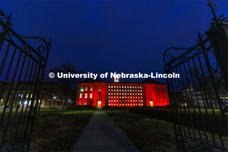 The gates to the Love Gardens frame the Love Library which is lit up red for Glow Big Red. February 16, 2022. Photo by Craig Chandler / University Communication.