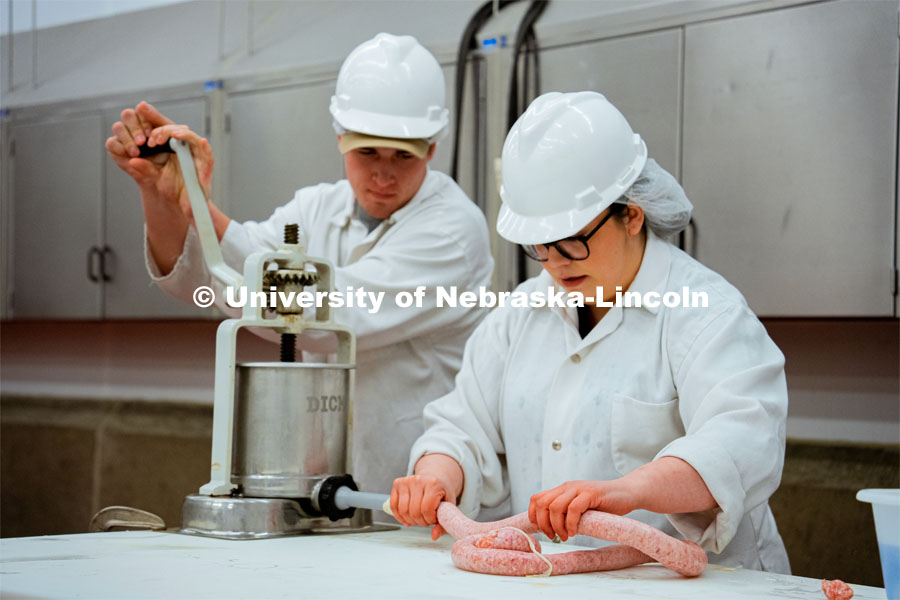 Leila Venzor and Frazier Kaelin demonstrate the sausage-making process. UNL Meat Science club had a Sausage Making 101 course in the Animal Science Complex. February 28, 2022. Photo by Jonah Tran / University Communication.