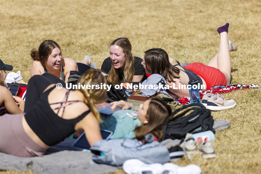 A group of young women take advantage of the nice weather and lay out and visit on the green space between the Union and the Kauffman Academic Residential Center. Spring on city campus. March 1, 2022. Photo by Craig Chandler / University Communication.