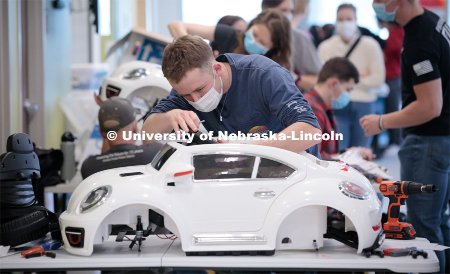 Ethan Bowles, a senior biological systems engineering major, makes an adjustment to the steering wheel in an electric car during the GoBabyGo! Build. His team is modifying the car for four-year-old Dayana Torres of Omaha. Bowles was among seven Huskers to assist with the project. This was his third time volunteering for the event.Twice yearly, Nebraska’s Go Baby Go chapter modifies kid-sized battery powered cars for children with movement difficulties, providing them at no cost to the families. Nebraska’s GoBabyGo! chapter is funded by the Munroe-Meyer Guild. The program is a partnership between MMI's Department of Physical Therapy, the University of Nebraska-Lincoln and the University of Nebraska-Omaha Engineering Department and the UNMC College of Allied Health Professions/Physical Therapy students. The event took place on at the MMI building at 69th and Pine Streets in Omaha on Saturday, April 2, 2022. Photo by Kent Sievers / University of Nebraska Medicine.
