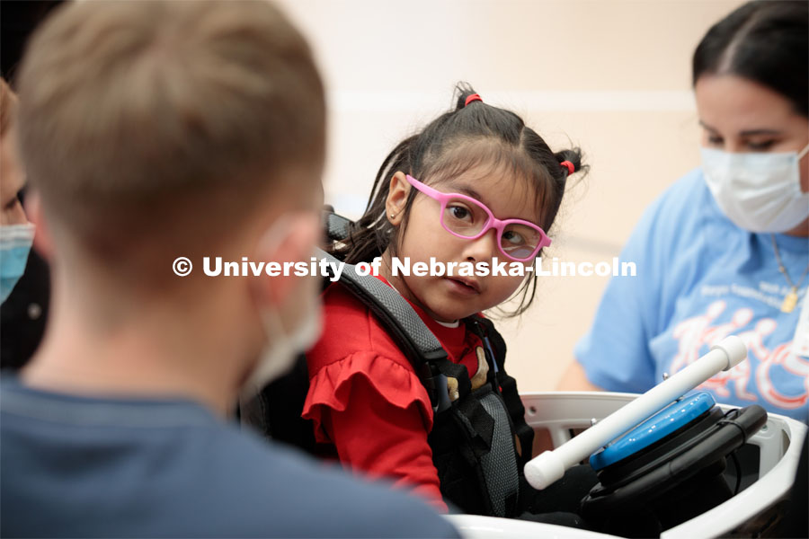 Four-year-old Dayana Torres looks at UNL engineering student Ethan Bowles, left, while being strapped into the new, battery-powered car that Bowles and his team modified for her.Twice yearly, Nebraska’s Go Baby Go chapter modifies kid-sized battery powered cars for children with movement difficulties, providing them at no cost to the families. Nebraska’s GoBabyGo! chapter is funded by the Munroe-Meyer Guild. The program is a partnership between MMI's Department of Physical Therapy, the University of Nebraska-Lincoln and the University of Nebraska-Omaha Engineering Department and the UNMC College of Allied Health Professions/Physical Therapy students. The event took place on at the MMI building at 69th and Pine Streets in Omaha on Saturday, April 2, 2022. Photo by Kent Sievers / University of Nebraska Medicine.